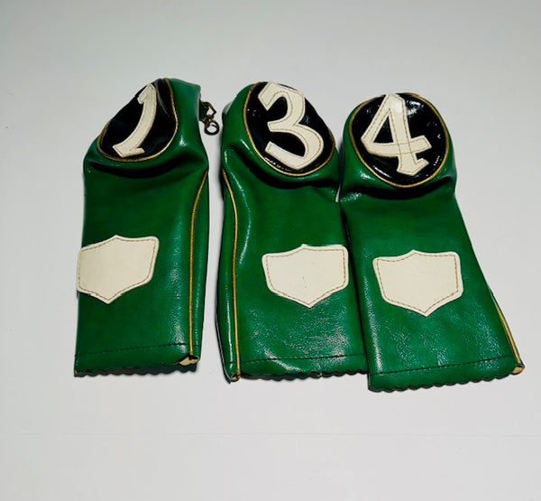 Vintage green leather golf headcover set numbered 1, 3 and 4 with ivory shields laid out