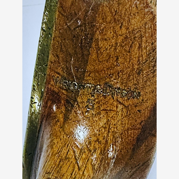 Close-up of the Wright & Ditson head stamp beside the brass face plate edge, hickory golf putter